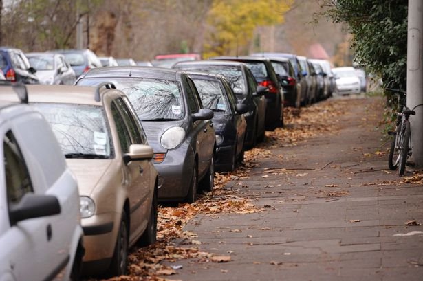 cars parked on the side of the street close to pavement